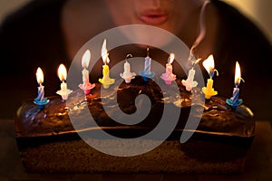 Woman is blowing out some colorful candles