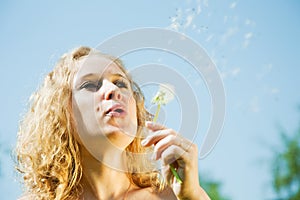 Woman blowing seeds of dandelion