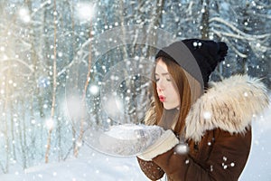 Woman blowing snow. Young woman at winter. Winter young woman portrait. Beautiful young woman laughing outdoors