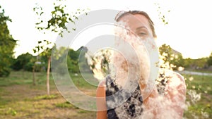 Woman blows on reeds outdoors in sunny day. Fluff from reeds flies around. Slow motion