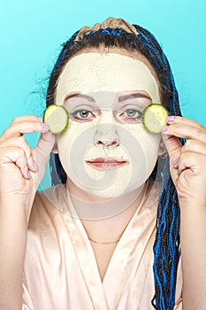 Woman with blue afro braids face in a frozen mask made of green clay.