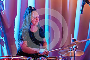 A woman with a blue afro hairstyle drummer plays drums during a concert