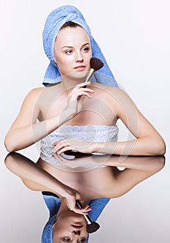 Woman in blue bath towel on head with makeup brush