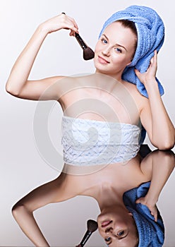 Woman in blue bath towel on head with makeup brush