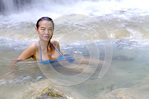 Woman with blue bikini happy in water at Erawan Waterfall