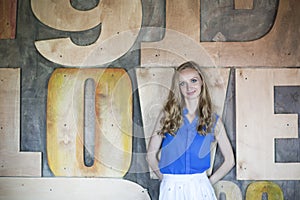 Woman in blue blouse staying in front of dark wall and keep smiling