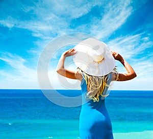 Woman in Blue Dress and Hat at Sea. Rear View.