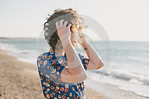 Woman in blue dress posing at beach on sunset.