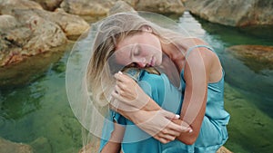 Woman in blue dress sits on rock amidst serene waters for tranquility. Reflecting emotional healing beside sea, finding