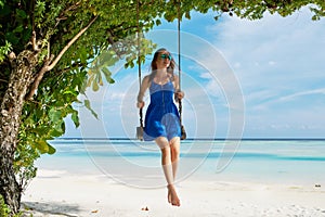 Woman in blue dress swinging at beach