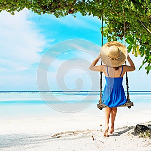 Woman in blue dress swinging at beach