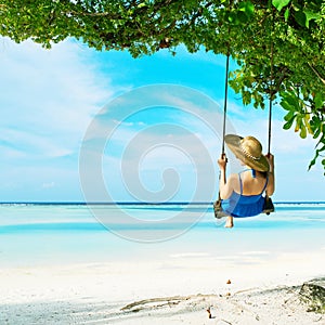 Woman in blue dress swinging at beach