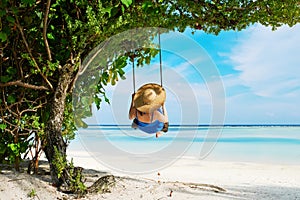 Woman in blue dress swinging at beach