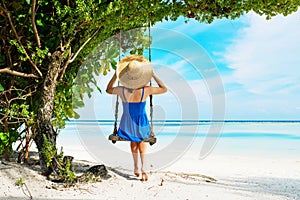 Woman in blue dress swinging at beach