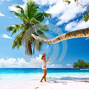 Woman in blue dress swinging at beach