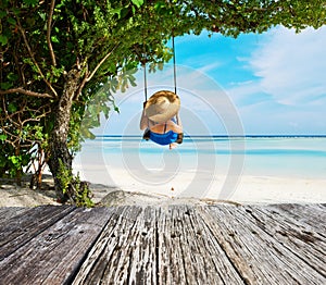 Woman in blue dress swinging at beach