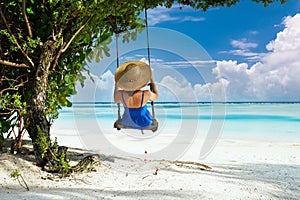 Woman in blue dress swinging at beach