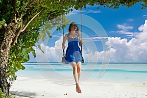 Woman in blue dress swinging at beach