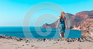 Woman with blue dress walking to beach