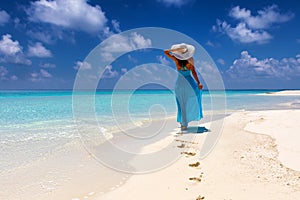 Woman in blue dress walks on a tropical beach