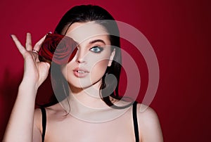 Woman with blue eyes and red rose flower. Fashion beauty portrait on studio background.