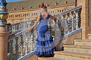 The woman in the blue flamenco dress, resting on the stairs