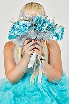 Woman in blue fluffy dress hides her face behind a photo