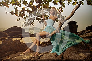 Woman In Blue Fluttering Dress Swinging On A Beach Swi