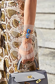 Woman with blue and golden spider bracelet and reptlie learther skirt before Genny fashion show