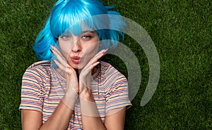 Woman with blue hair pouting lips on grass