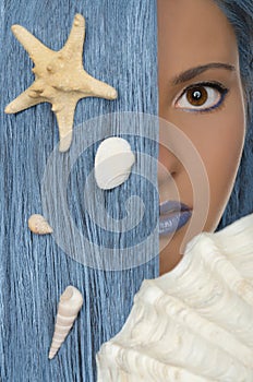 Woman with blue hair, shells, looking at camera