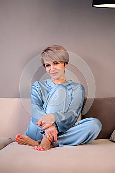 woman in a blue home suit sitting on the sofa