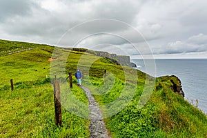 Woman in blue jacket enjoying the coastal walk route from Doolin to the Cliffs of Moher