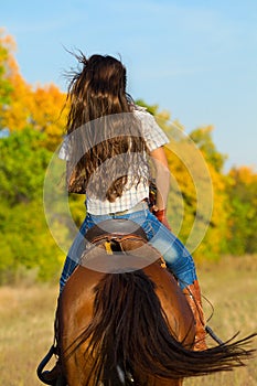 Woman in blue jeans riding a horse