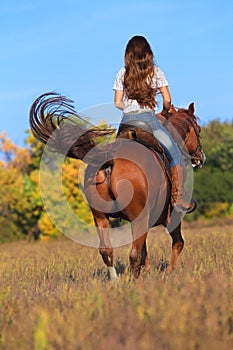 Woman in blue jeans riding a horse