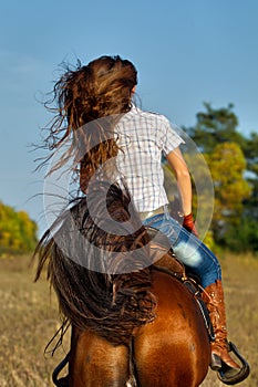 Woman in blue jeans riding a horse