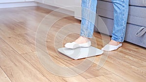 Woman in blue jeans weighing herself on floor scales