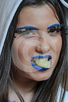 Woman with blue lipstick and unique makeup eaitng a pineapple