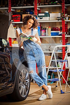 Woman in blue overalls studying the instructions for vehicle adjustment