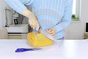 A woman in blue pullover unpacks, unbox an orange parcel with a kitchen knife