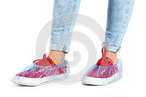 Woman with blue shoe covers worn over sneakers on white background