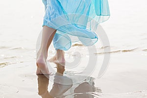 Woman with blue skirt walking on the beach