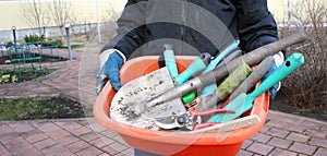 Woman in blue sport suit holding diffrent garden tools.