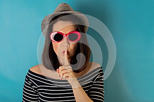 Woman in blue striped top, grey hat and red sunglasses on a blue