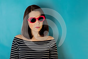 Woman in blue striped top and red sunglasses on a blue background.