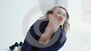 A woman in a blue suit poses and grimaces in a photo studio. businesswoman