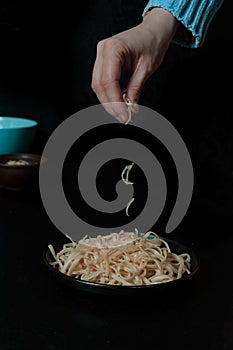 Woman in a blue sweater sprinkled with cheese on chicken spaghetti.