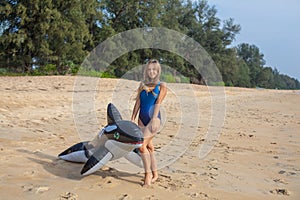 woman in blue swimsuit on the beach with inflatable toy