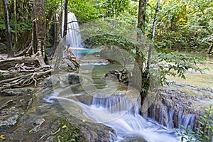 Woman in blue swimsuit sit look  Erawan Waterfall and natural