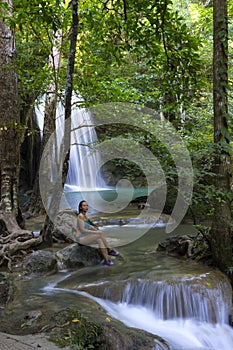 Woman in blue swimsuit sit relax at Erawan Waterfall and natura